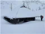 Pastirska koča na Planini Koren je skoraj do strehe v snegu.