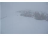 Tik pred kočo, ki je za skalami proti desni strani slike, tukaj je edino malo večje snežišče